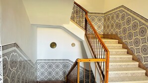 A staircase with intricate tile patterns and a wooden handrail. - Large apartment with Rooftop in a private, secure, family-friendly building! (Al Aaroui)