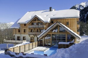 A large wooden chalet with multiple balconies and a glass entrance, surrounded by snow and mountains. - Swimming pool, sauna, tv, 55m², Saint Colomban des Villards (Saint-Colomban-des-Villards)