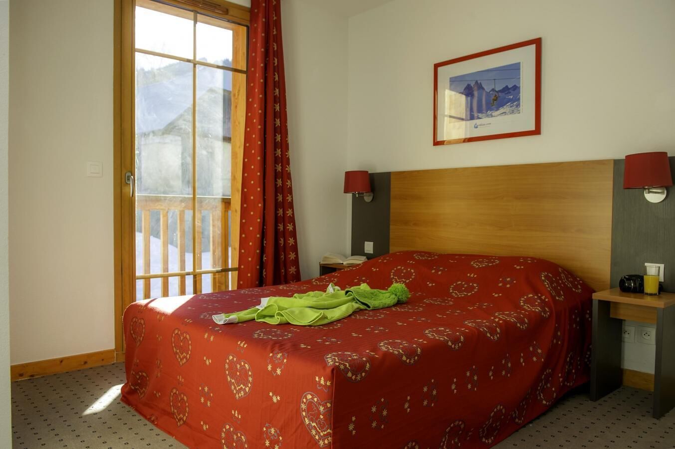 A hotel room with a bed, two bedside lamps, a framed picture on the wall, and a window with curtains.