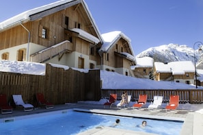 A wooden building with a pool area, surrounded by snow-covered mountains.