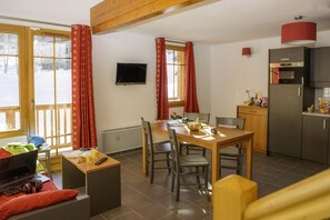 A cozy room with a wooden dining table, chairs, a laptop, and a TV on the wall. - Swimming pool, sauna, tv, 70m², Saint Colomban des Villards (Saint-Colomban-des-Villards)