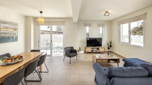 Uma sala de estar moderna com sofá, TV, mesa de jantar e cadeiras.