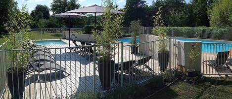 A backyard with a swimming pool, patio furniture, and a fenced area.