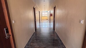 Un pasillo con piso de mármol, puertas de madera y vista a una habitación con ventana.