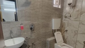 Un baño moderno con lavamanos, inodoro y ducha.