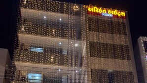 Un edificio de varios pisos, cada uno decorado con guirnaldas luminosas. Se leen los carteles 