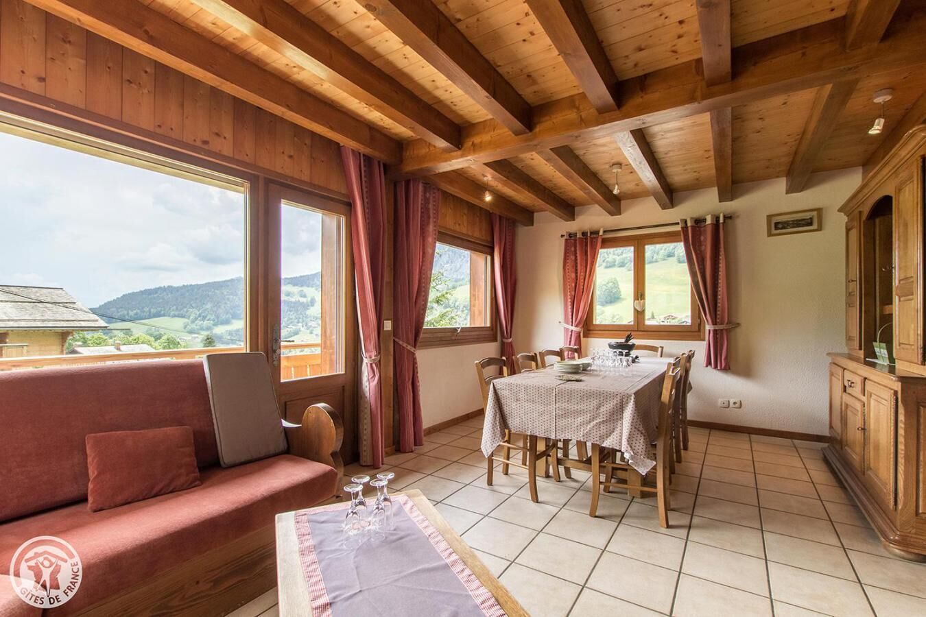 Ein Holzinterieur mit Esstisch, Stühlen, einer Couch und Blick ins Freie.