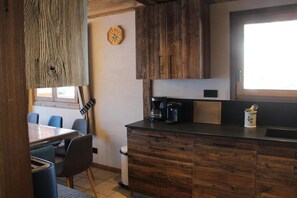 A kitchen with wooden cabinets, a coffee maker, and a clock on the wall.
