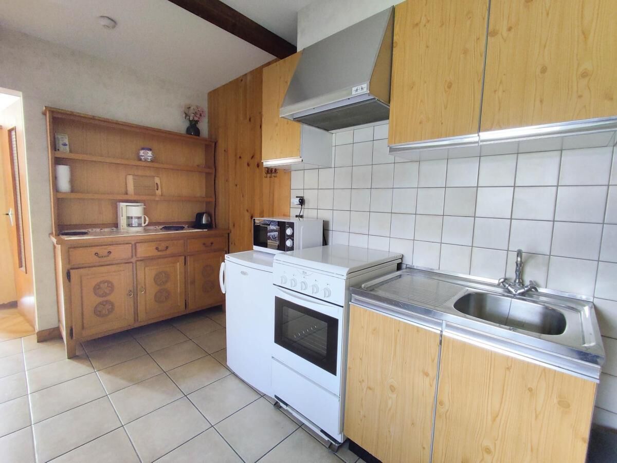 A kitchen with wooden cabinets, a white stove, a microwave, and a stainless steel sink.