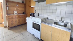 Una cocina con armarios de madera, una estufa blanca, un microondas y un lavamanos de acero inoxidable.