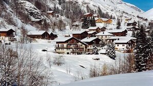 Un pueblo cubierto de nieve en la montaña, con casas de madera y una pista de esquí.