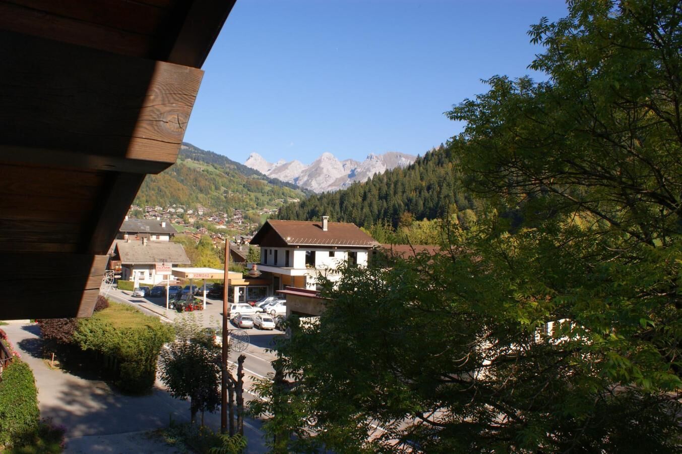 A mountain town with a view of snow-capped peaks, a parking lot, and a building with a sloped roof.