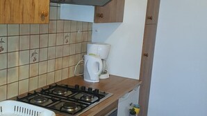 Una cocina compacta con gabinetes de madera, estufa a gas, cafetera y lavavajillas.