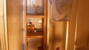 Un baño pequeño con estantes de madera, un perchero y un taburete de madera.