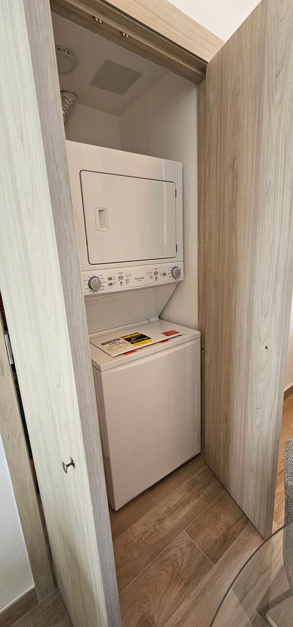 A compact laundry room with a built-in washer and dryer, wooden paneling, and a tiled floor. - The Beach Spacious 2 Bedroom 2 Bath Apartment on top Floor With Stunning Views (Punta Cana)
