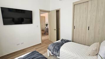 Un dormitorio con una cama, un televisor montado en la pared y un armario de madera.