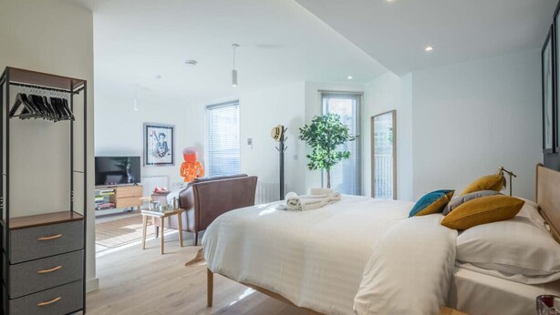 Een moderne slaapkamer met een groot bed, een kledingkast, een bureau en een televisie.