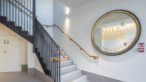 Een trap met een leuning die leidt naar een bord met daarop 'WELCOME TO MILL HOUSE CAMBRIDGE'.