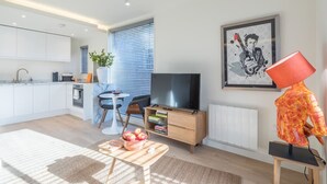 Een moderne woonkamer met een flatscreen-tv, een eettafel met appels en een bijzondere sculptuur.