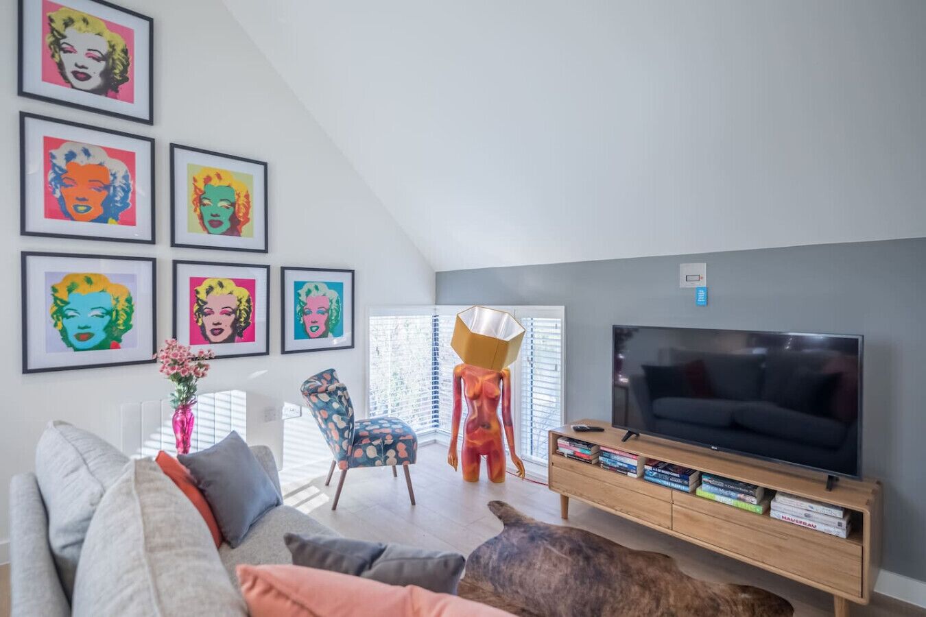 A modern living room with a TV, bookshelves, and colorful artwork on the wall.
