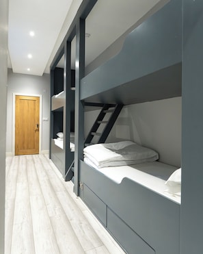 A modern room with bunk beds, a wooden door, and a light-colored wooden floor.