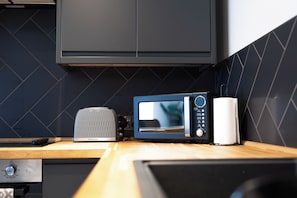 A kitchen with a toaster, a microwave, and a roll of paper towels on a wooden countertop.