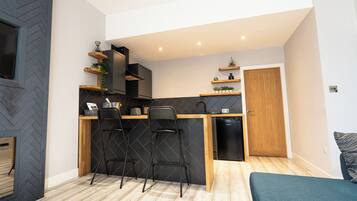 Una cocina compacta con encimera de madera, dos taburetes negros y lavavajillas integrado.