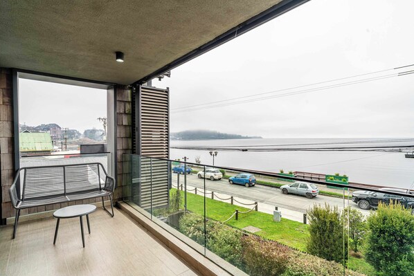 Un balcon donnant sur une rivière, avec une table et un banc.