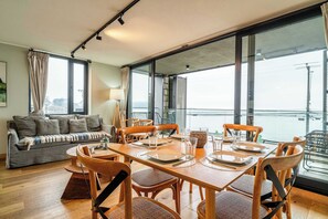 A dining area with a table set for four, wooden chairs, and a sofa in the background.