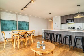 Una cocina moderna con microondas, cafetera y taburetes de bar.