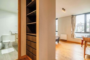 Un appartement moderne doté d’une armoire en bois, de toilettes, d’un radiateur et d’un coin repas avec une table et des chaises.