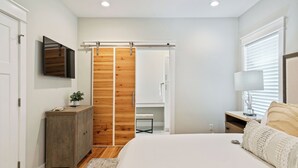 A bedroom with a bed, a wardrobe, a TV, and a bedside table. - Blue Mountain Beach Retreat | Pet-Friendly | Private Pool | 5 Bikes (Santa Rosa Beach)