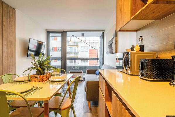 Una cocina compacta con comedor, un televisor en la pared y vistas al exterior.