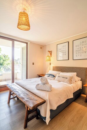 A bedroom with a bed, bench, and a large window.