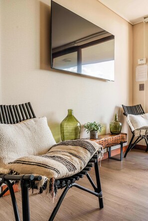 A room with a sofa, a television, and decorative bottles.