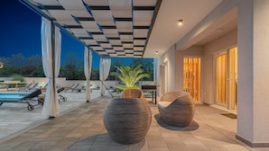Une terrasse extérieure avec une piscine, des chaises longues et deux grands jardinières à motifs.
