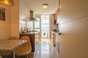 A compact kitchen with a dining area, a washing machine, and a large window.