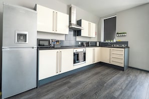 A modern kitchen with a built-in refrigerator, oven, microwave, and a stainless steel range hood.