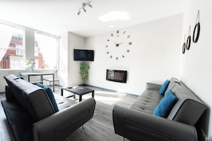 A modern living room with a sofa, a coffee table, and a TV mounted on the wall.