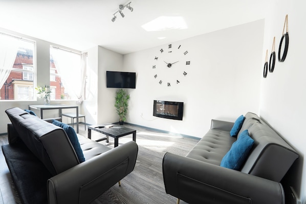 A modern living room with a sofa, a coffee table, and a TV mounted on the wall.