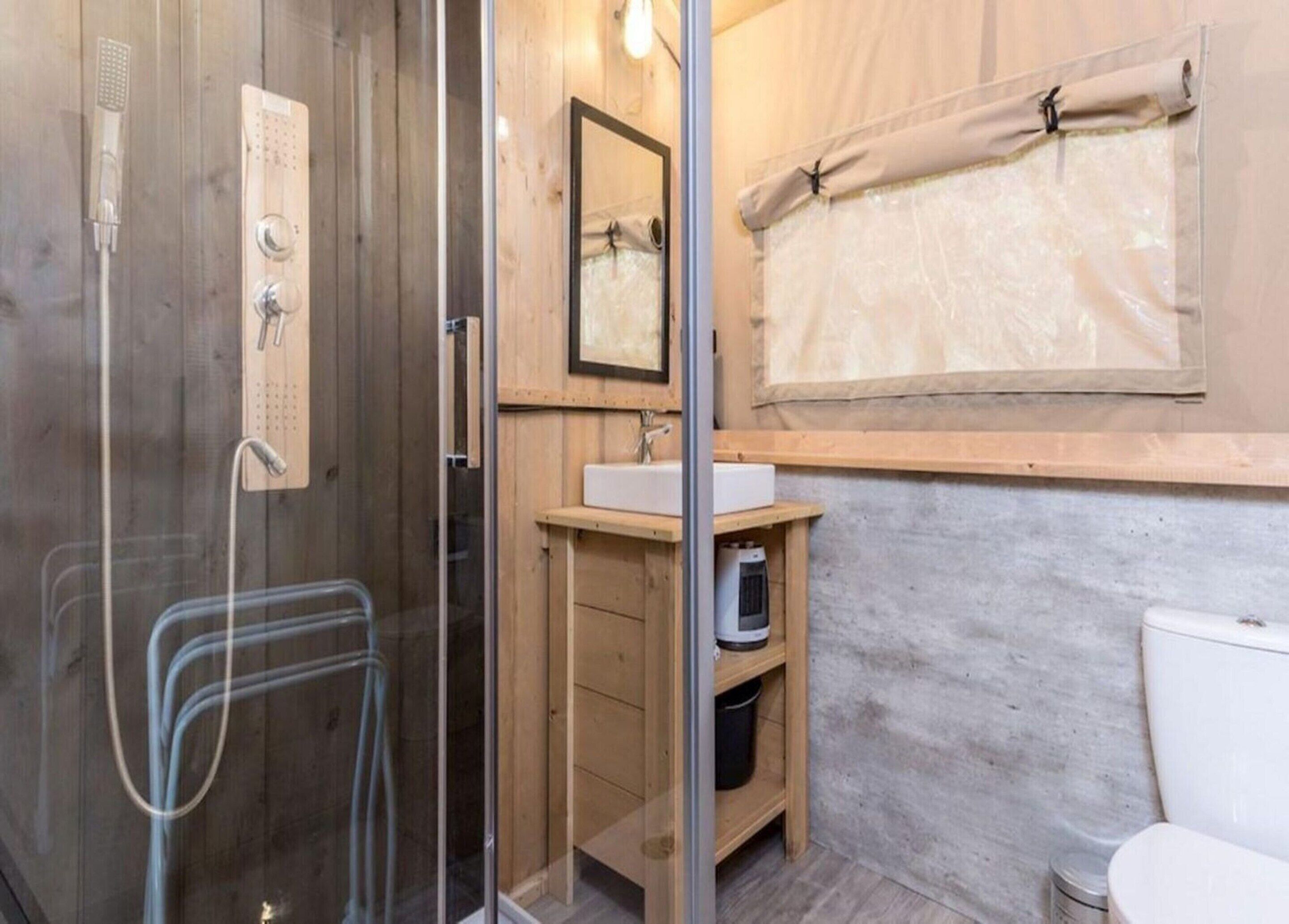 A bathroom with a glass shower enclosure, a wooden vanity with a sink, and a toilet.