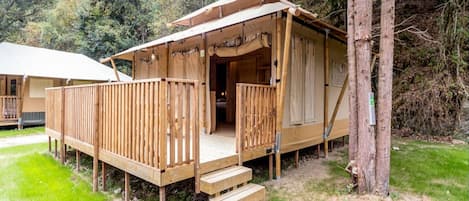 A wooden cabin with a deck, a staircase, and a covered entrance.