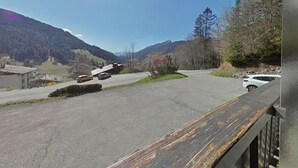 A parking area with a view of mountains, a wooden fence, and a building in the background. - Ground floor, view village, balcony, tv, 22m², Le Grand Bornand (Le Grand-Bornand)