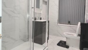 A modern bathroom with a glass-enclosed shower, a toilet, and a sink. - Desborough Apartment Retreat (Kettering)