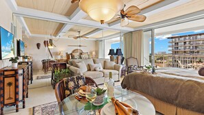 Amplia sala de estar con mesa de vidrio, asientos cómodos y una cama grande con vista al balcón.