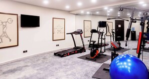 Een fitnessruimte met trainingsapparatuur, een loopband en een blauwe trainingsbal.