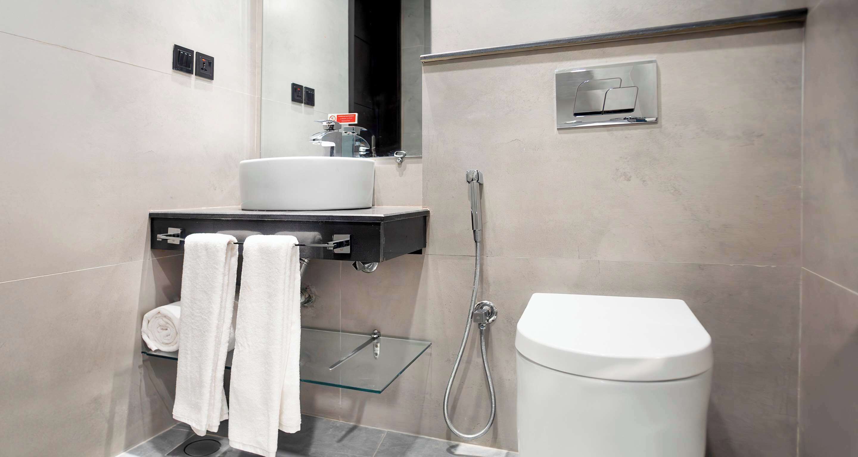 Un baño moderno con cabina de ducha de vidrio, inodoro blanco y lavamanos con toallero.