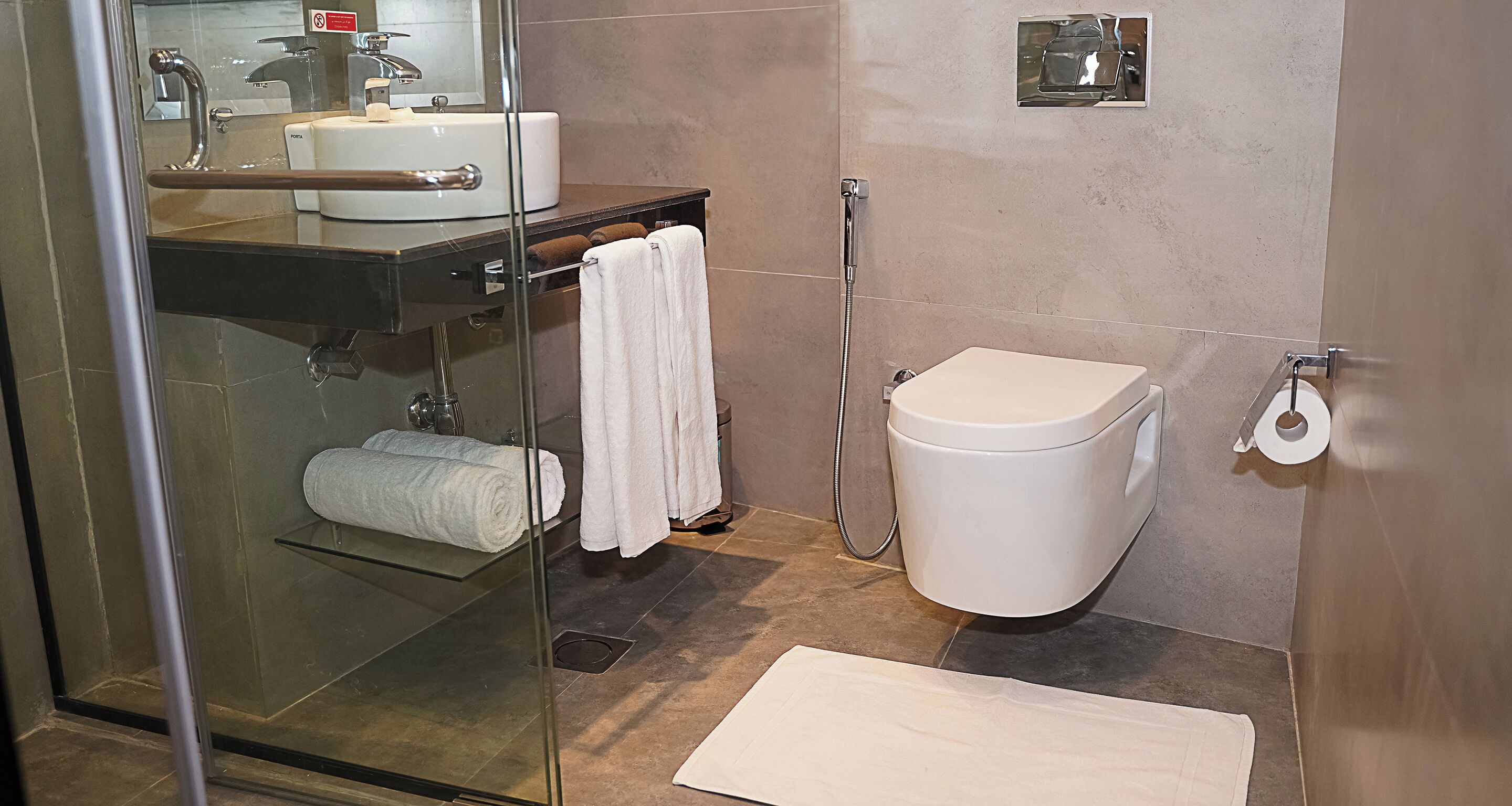 A modern bathroom with a glass shower enclosure, a white toilet, and a sink with a mirror above it.
