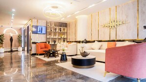 Un hall d’hôtel moderne avec un sol en marbre, un canapé, une table basse et un téléviseur fixé au mur.