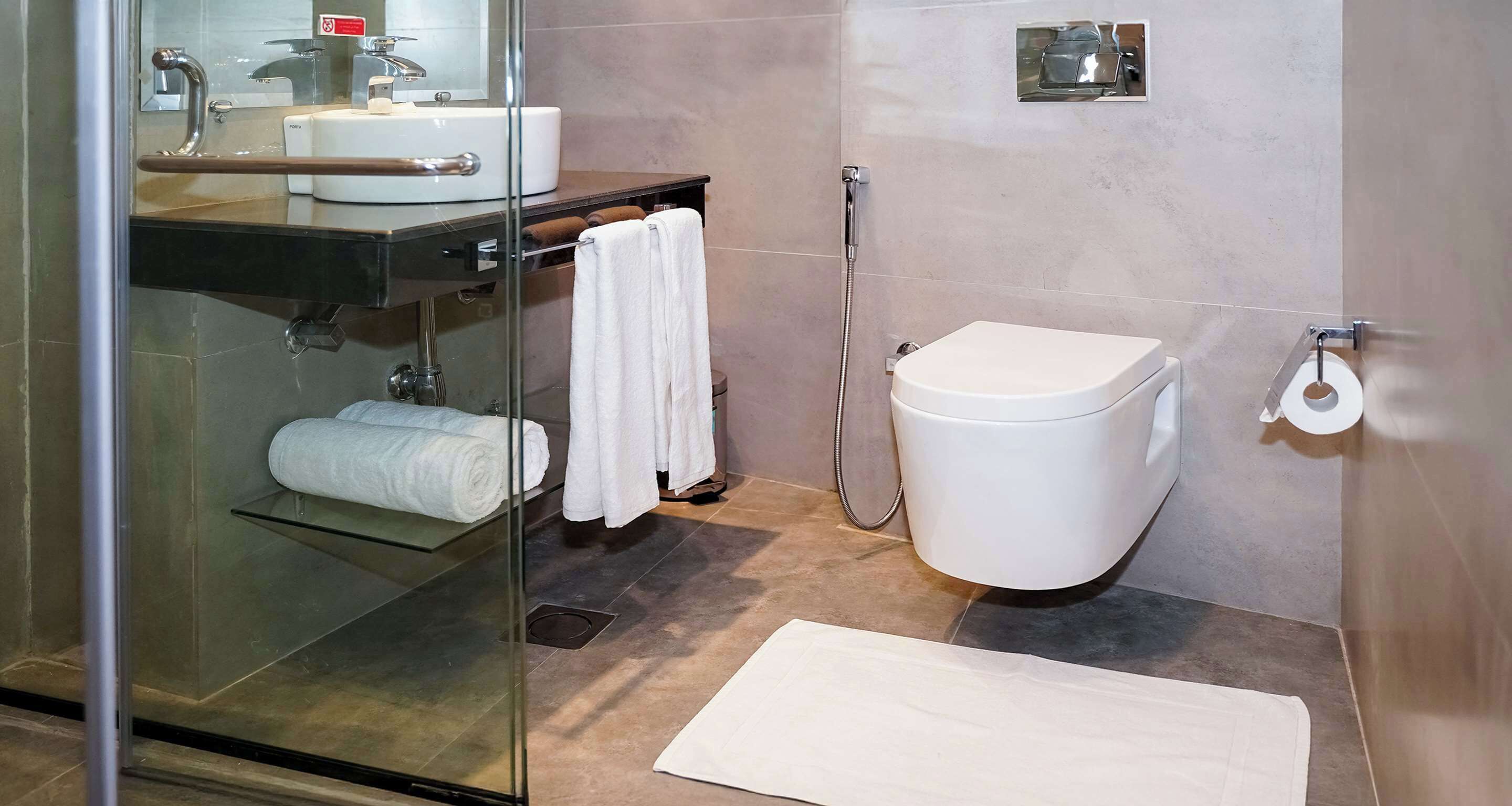 Un bagno moderno con box doccia in vetro, un water bianco e un lavandino con porta asciugamani.